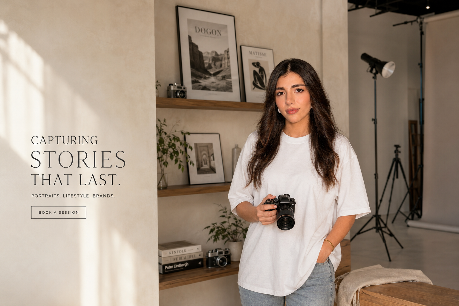 Photographer in a sunlit studio holding a camera, surrounded by framed prints and vintage cameras